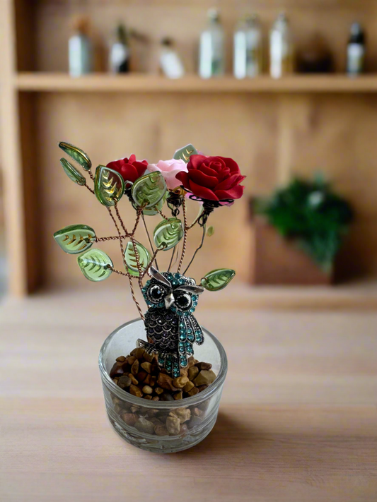 A bird next to three flowers in a glass container